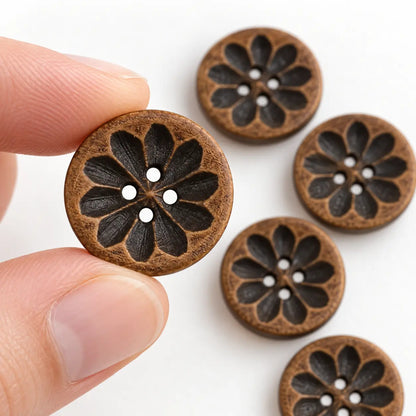 An 18 mm carved wooden four-hole button held between fingertips