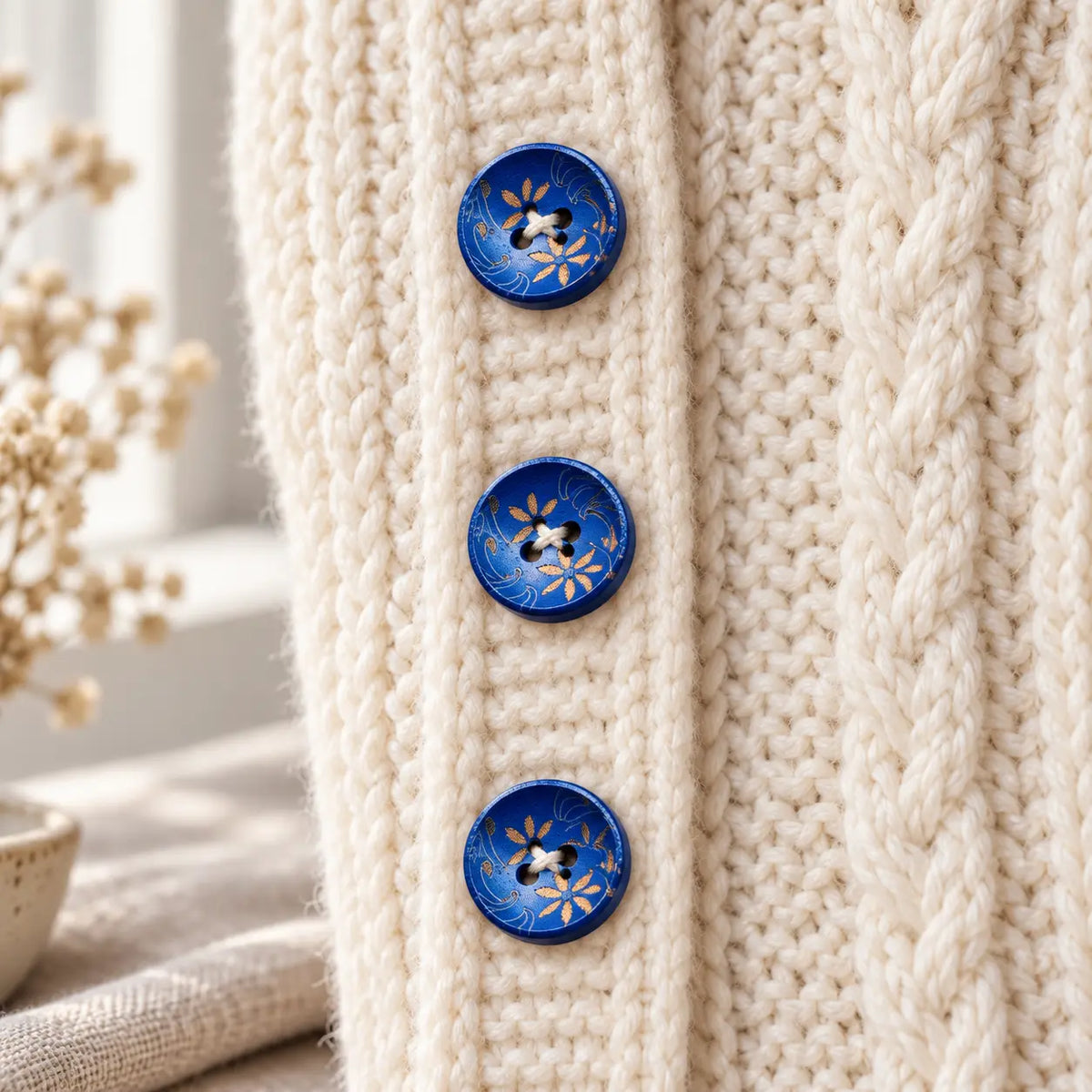 Blue-and-gold four-hole wooden buttons sewn onto a cream knit cardigan; cardigan not included