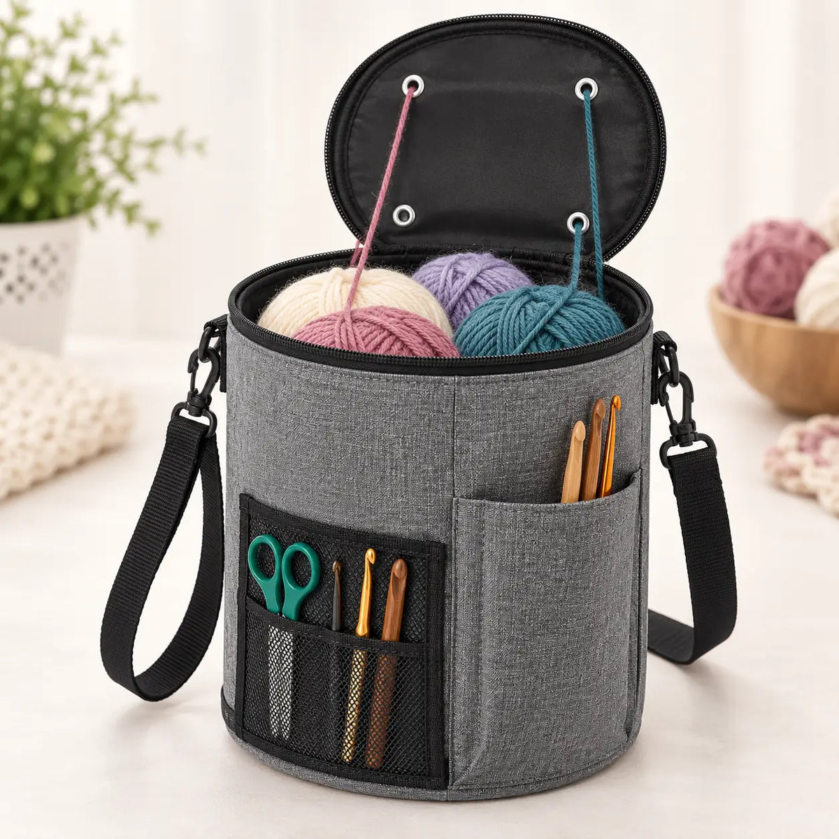 Grey cylindrical yarn organizer bag open with yarn and tools for demonstration; accessories not included