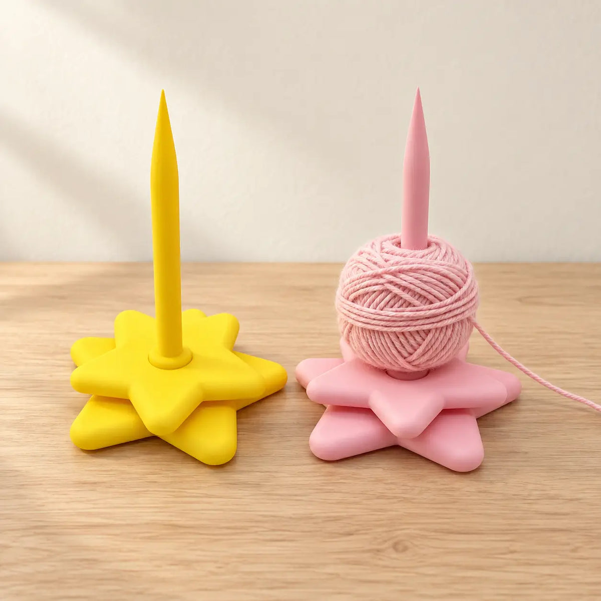 Yellow and pink rotating star yarn holders with pink yarn shown for demonstration; yarn not included